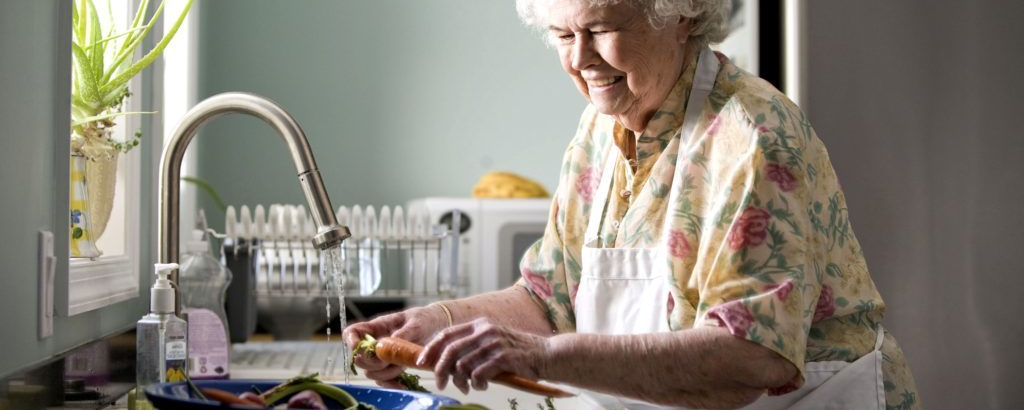 Elderly woman washing vegetables