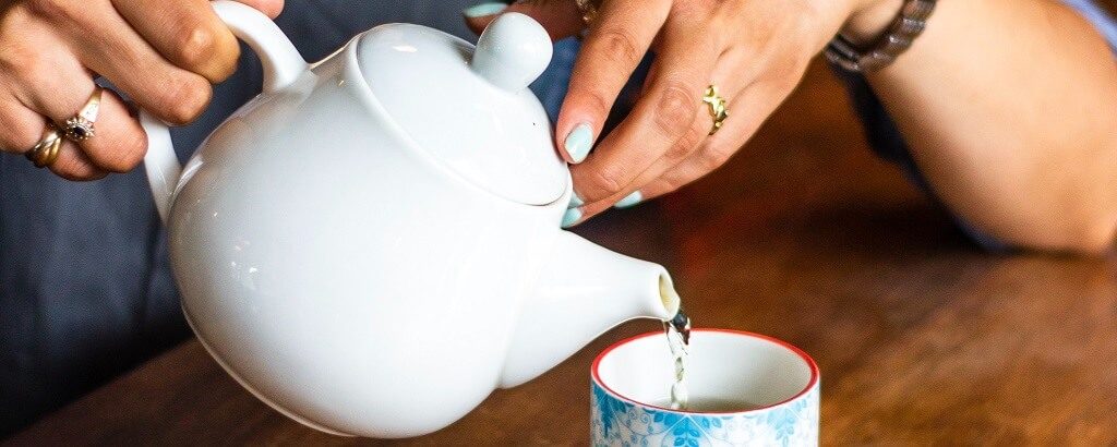 elderly person pouring tea for a friend to fight loneliness